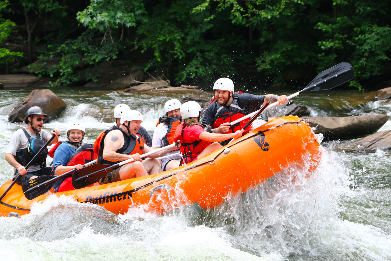 Conquer the rapids a group of people riding on the back of a boat in the water